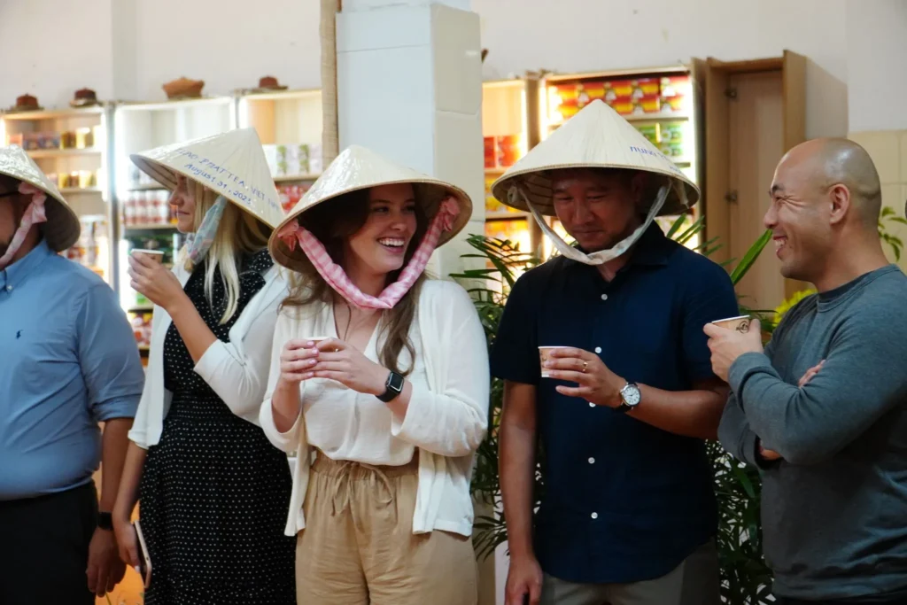 Experiencing Vietnamese culture through a tea tasting event: A group of people wearing traditional conical hats (non la) enjoy authentic Vietnamese tea and embrace the local customs and flavors.