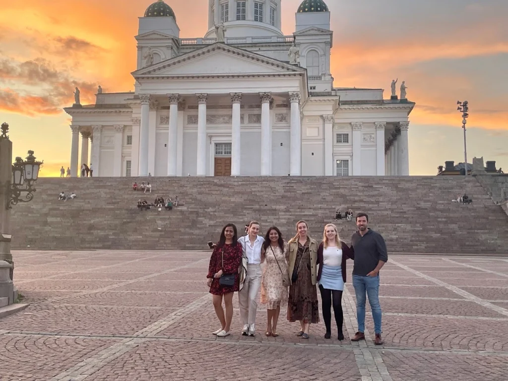 Group of people posing in front of Helsinki Cathedral at sunset