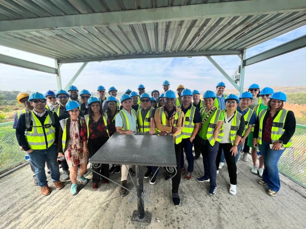 Group of engineers and students on an industrial site tour wearing blue hard hats and safety vests