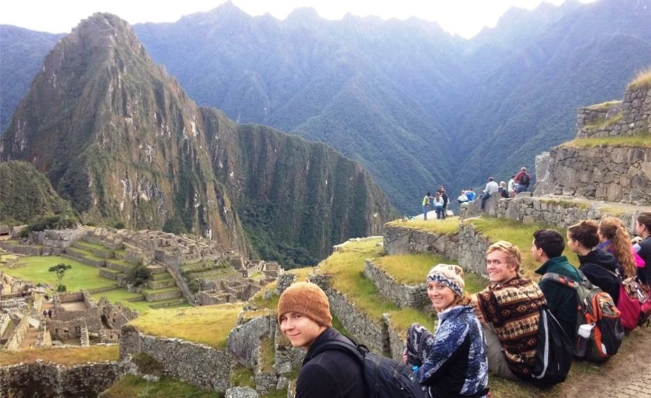 Group of tourists enjoying the scenic view of Machu Picchu ruins and Huayna Picchu mountain in Peru.