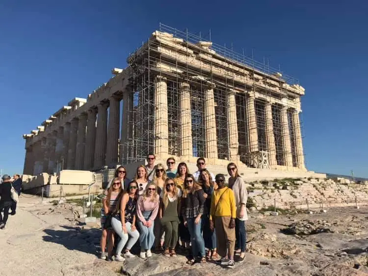 Group of tourists posing in front of the Parthenon in Athens, Greece.