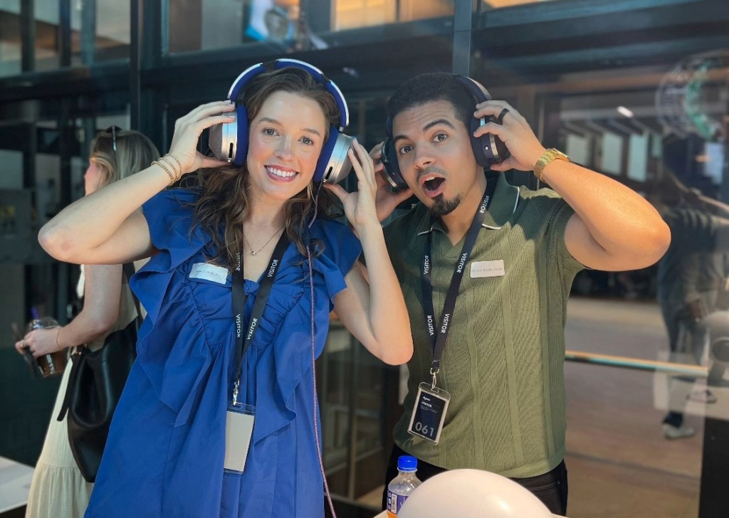 Two smiling people wearing headphones at an event.