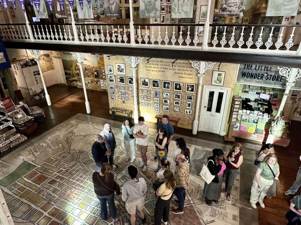 Visitors exploring a historical museum exhibit with a large floor map and wall displays.